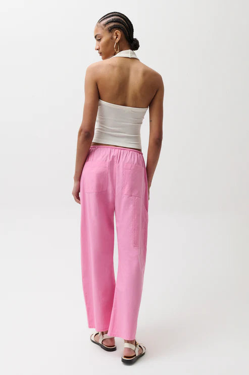 Woman wearing a white strapless top and pink pants on a white background