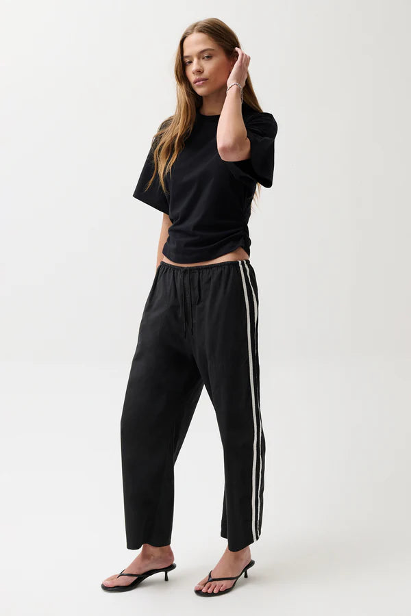 Woman wearing a black outfit with white stripes on a white background