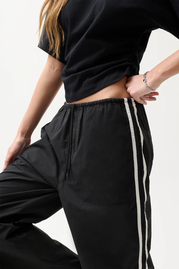 Person wearing black pants with a white stripe on a light background