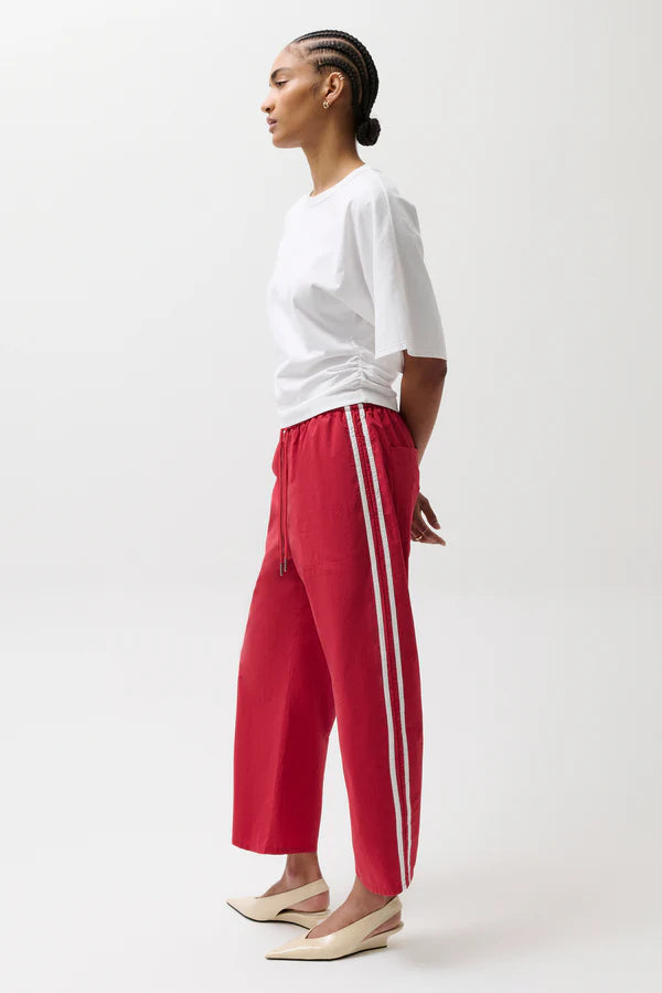 Person wearing a white top and red pants with white stripes on a white background