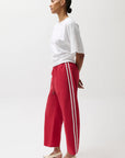 Person wearing a white top and red pants with white stripes on a white background