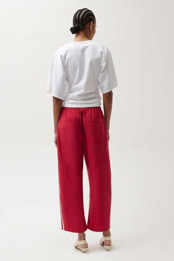 Person wearing a white top and red pants on a white background