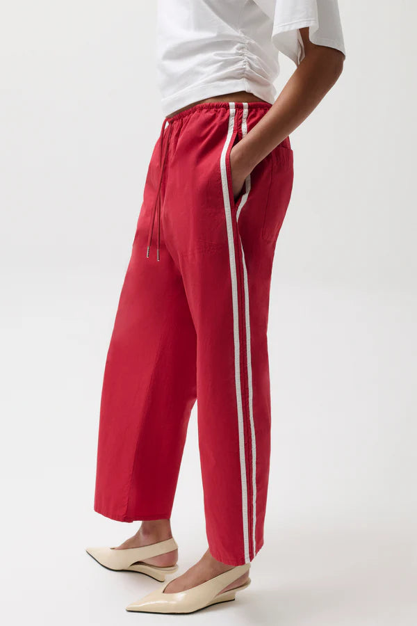 Red pants with white stripes worn by a person on a white background
