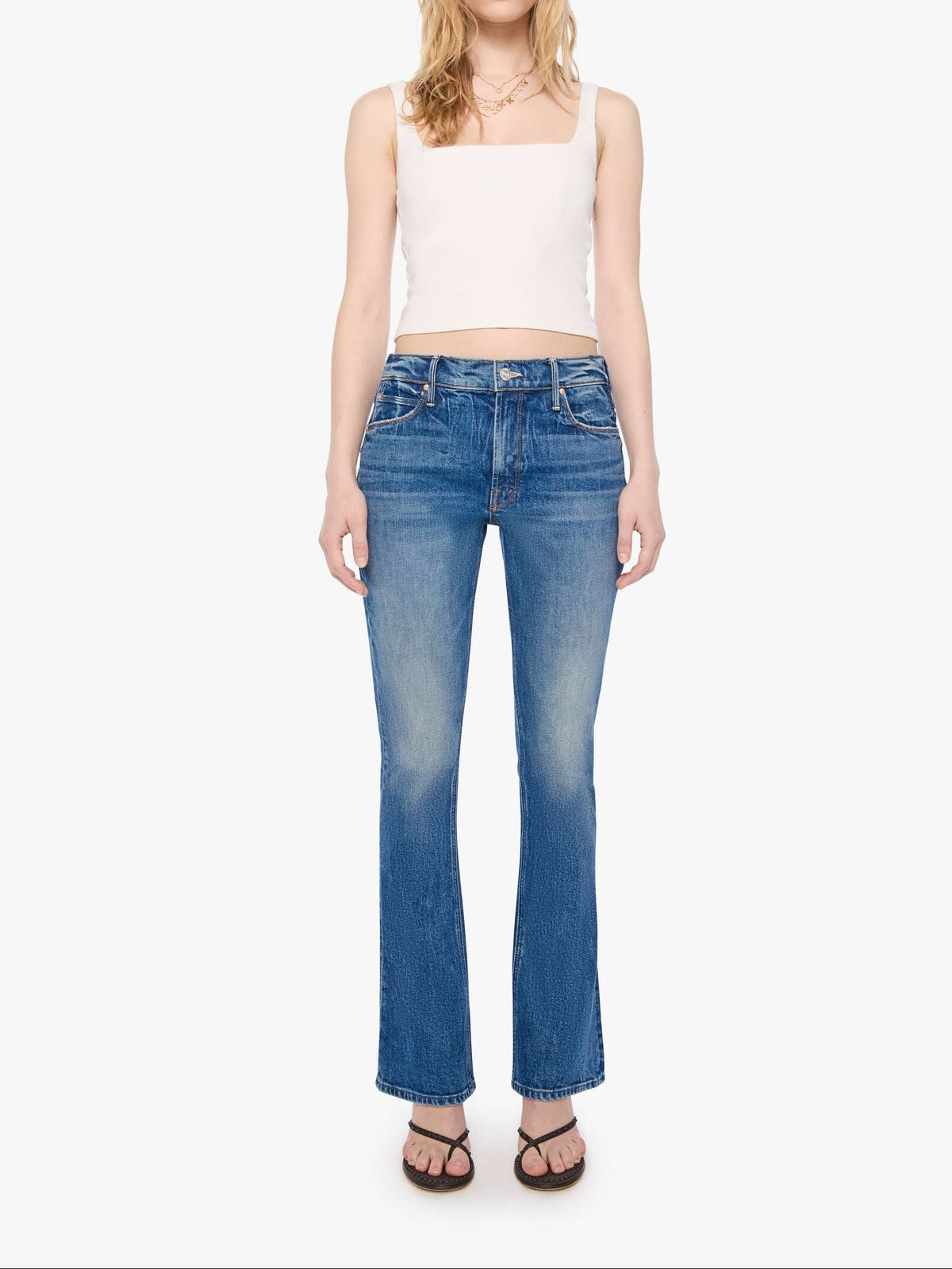 Woman wearing blue jeans and a white top on a white background