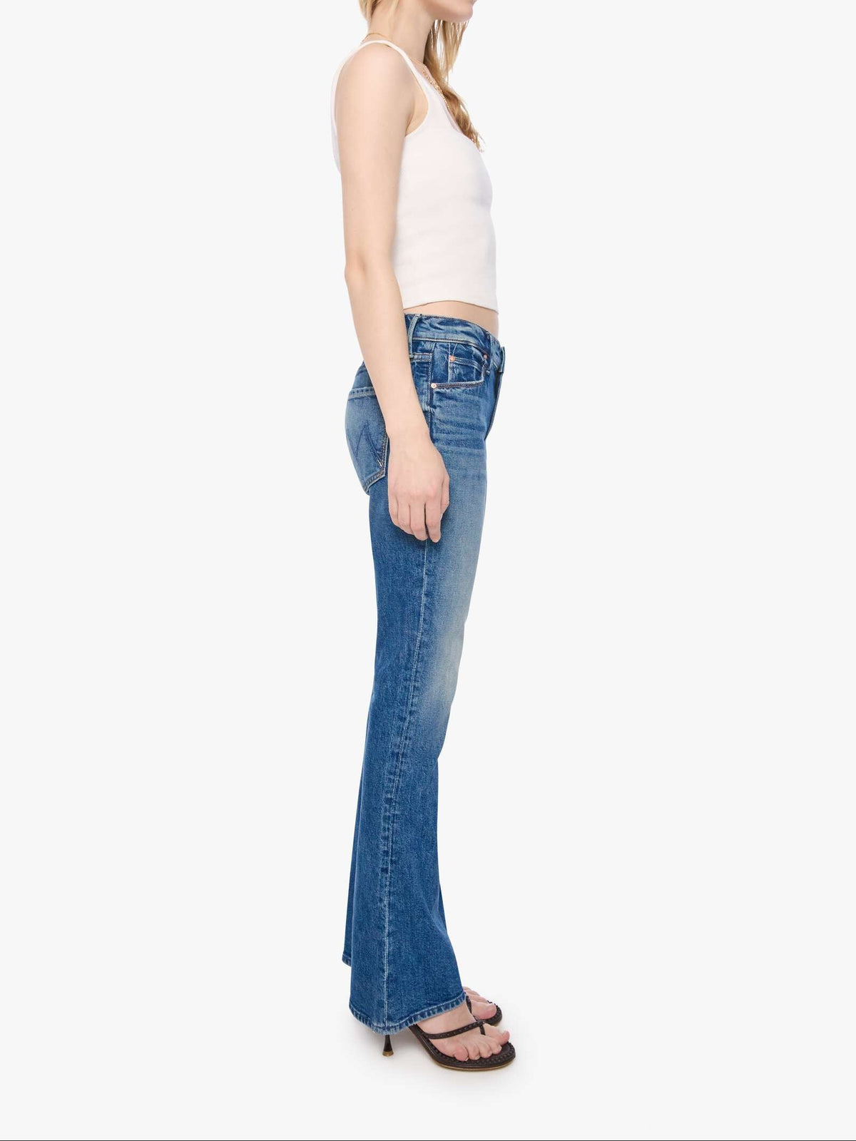 Woman wearing blue flared jeans and a white top on a white background