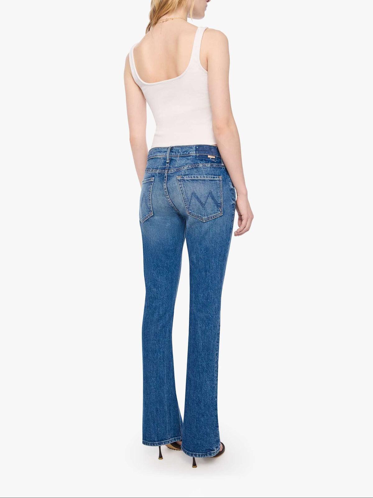 Woman wearing blue jeans and a white top on a white background