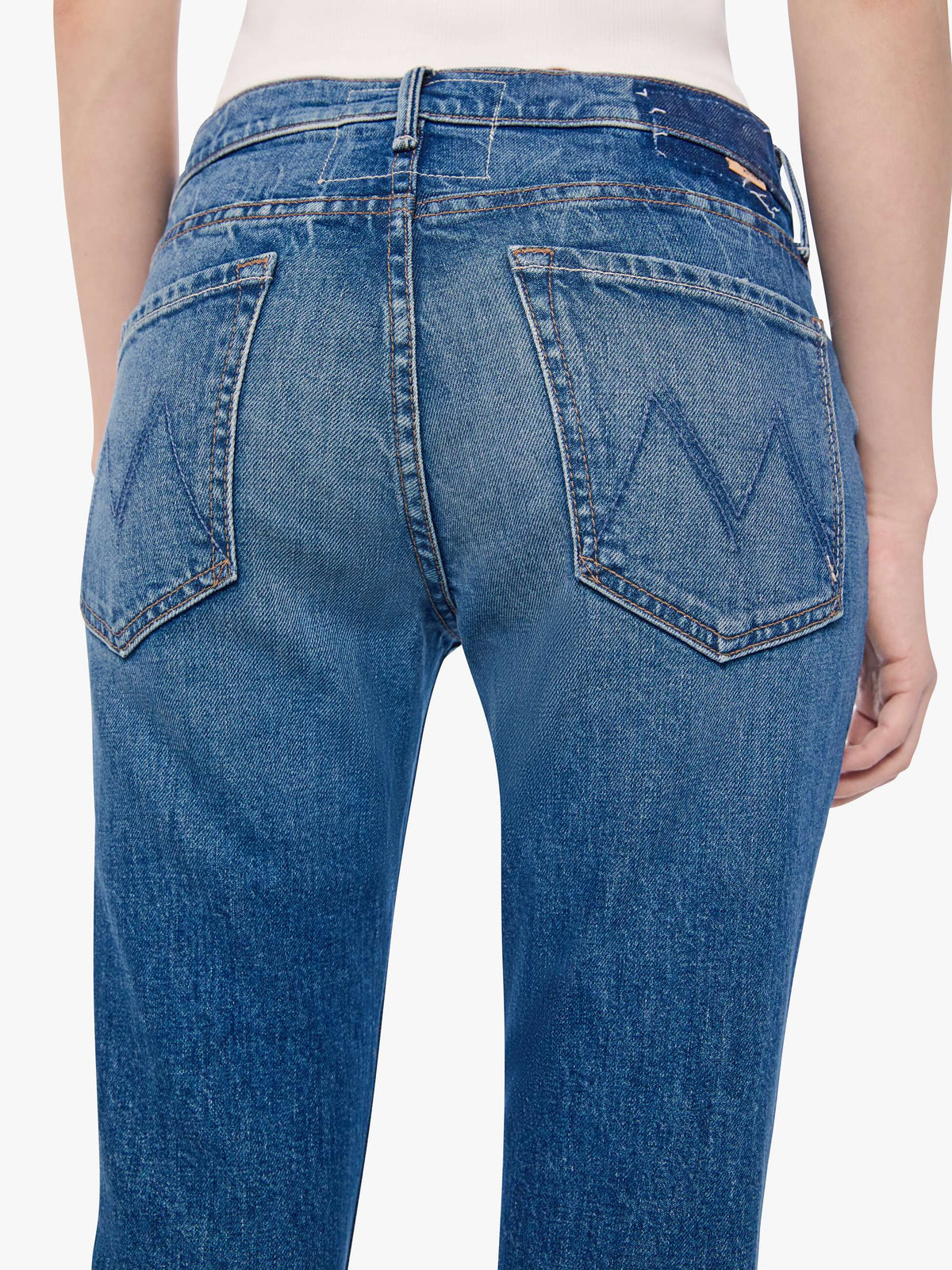 Blue jeans with a brand logo on the back pocket against a white background