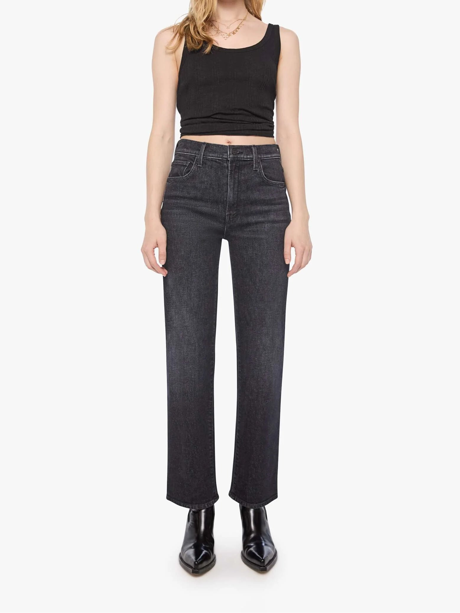 Woman wearing black sleeveless top and dark jeans on a white background