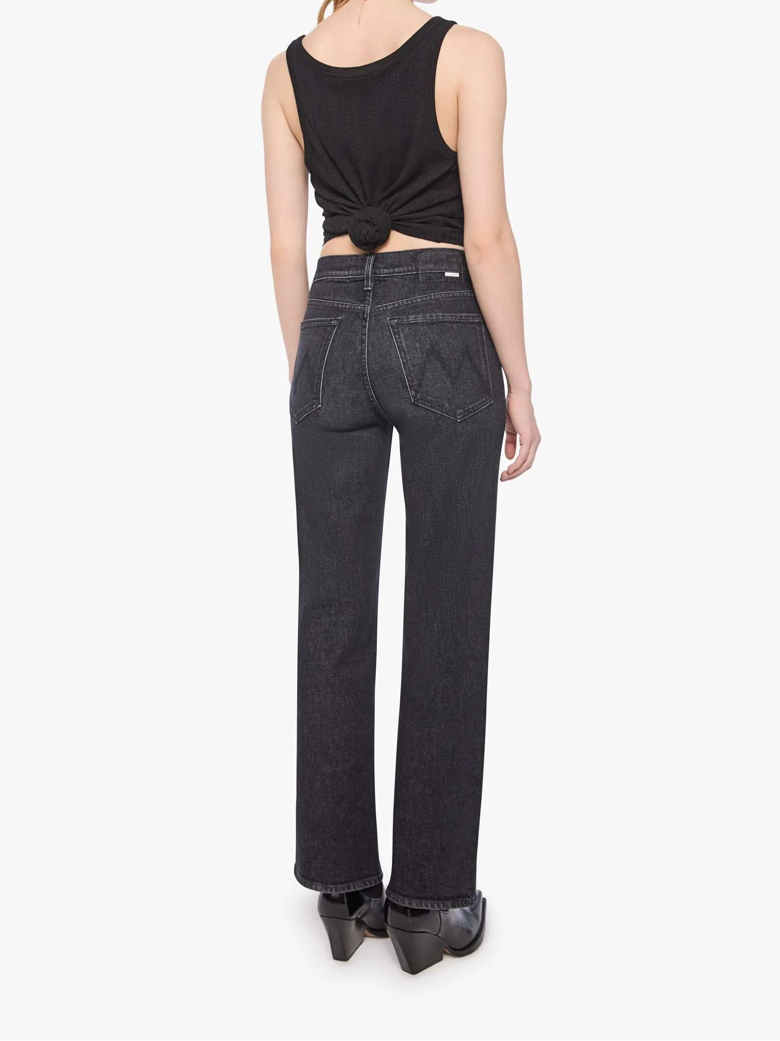 Woman wearing black tank top and jeans on a white background
