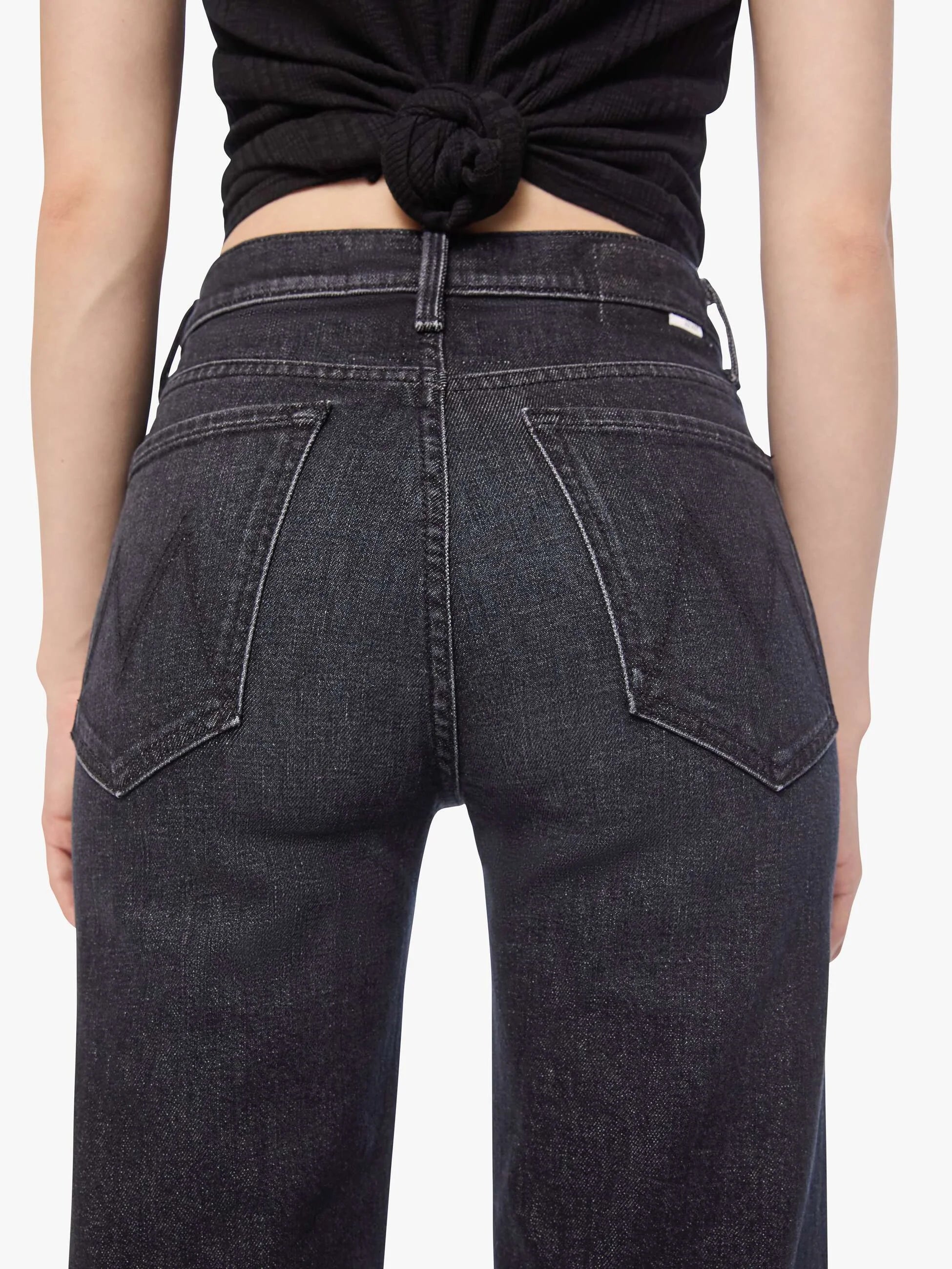 Woman wearing black tank top and jeans on a white background