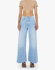 Woman wearing a beige crop top and light blue jeans on a white background