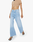 Woman wearing a beige crop top and light blue jeans on a white background