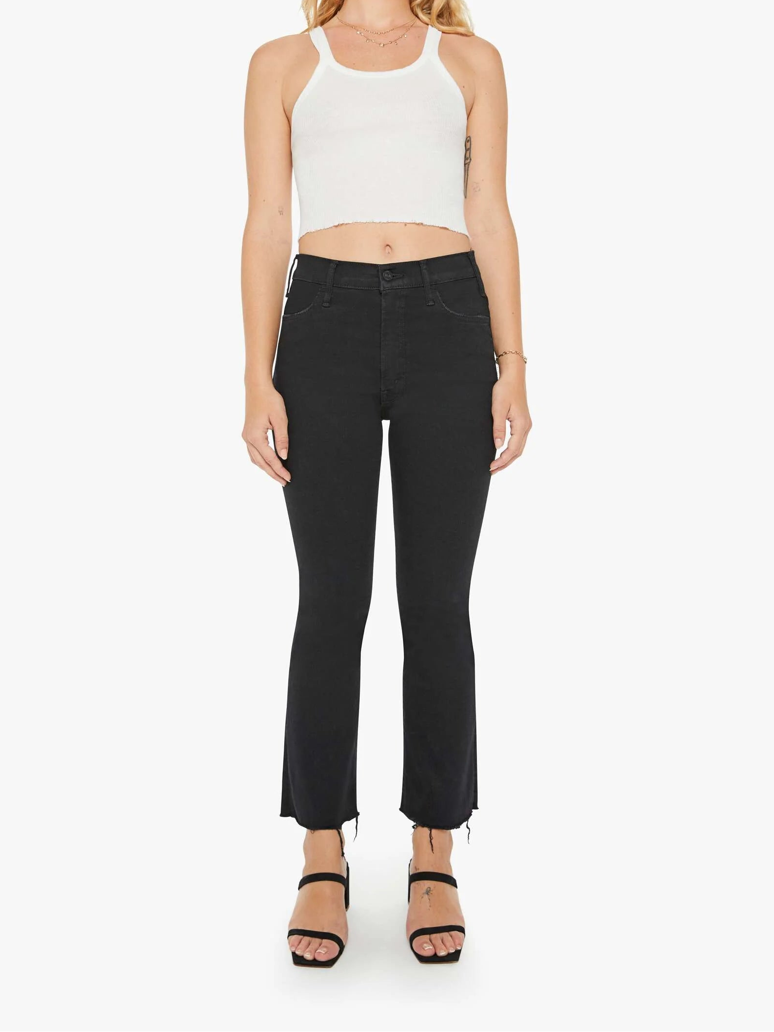 Woman wearing a white tank top and black pants on a white background