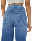 Blue jeans worn by a person on a plain background