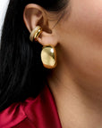 Close-up of a person wearing gold earrings with a blurred background