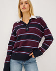stripe polo top worn by a model with jeans on a grey background 