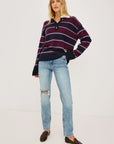 stripe polo top worn by a model with jeans on a grey background 