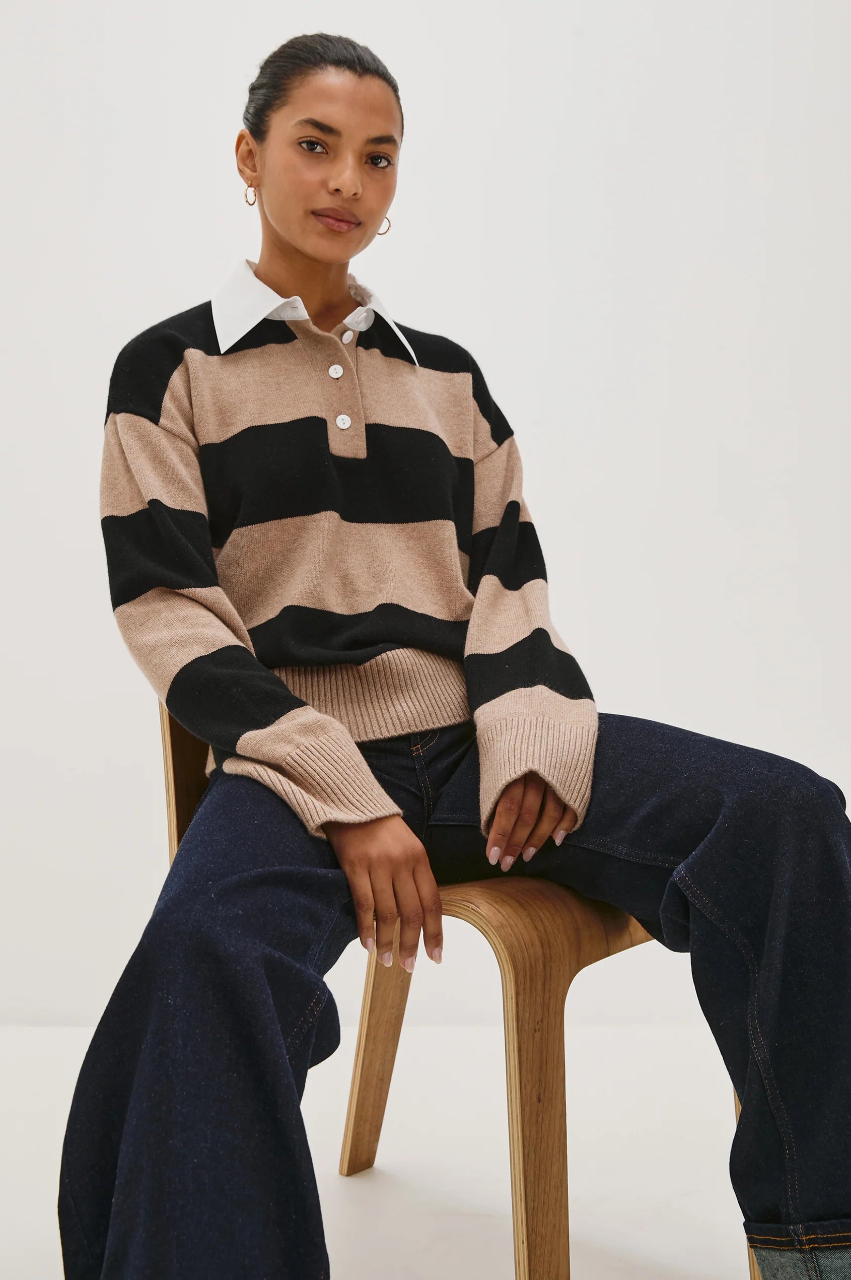 Person wearing a striped sweater sitting on a chair against a white background