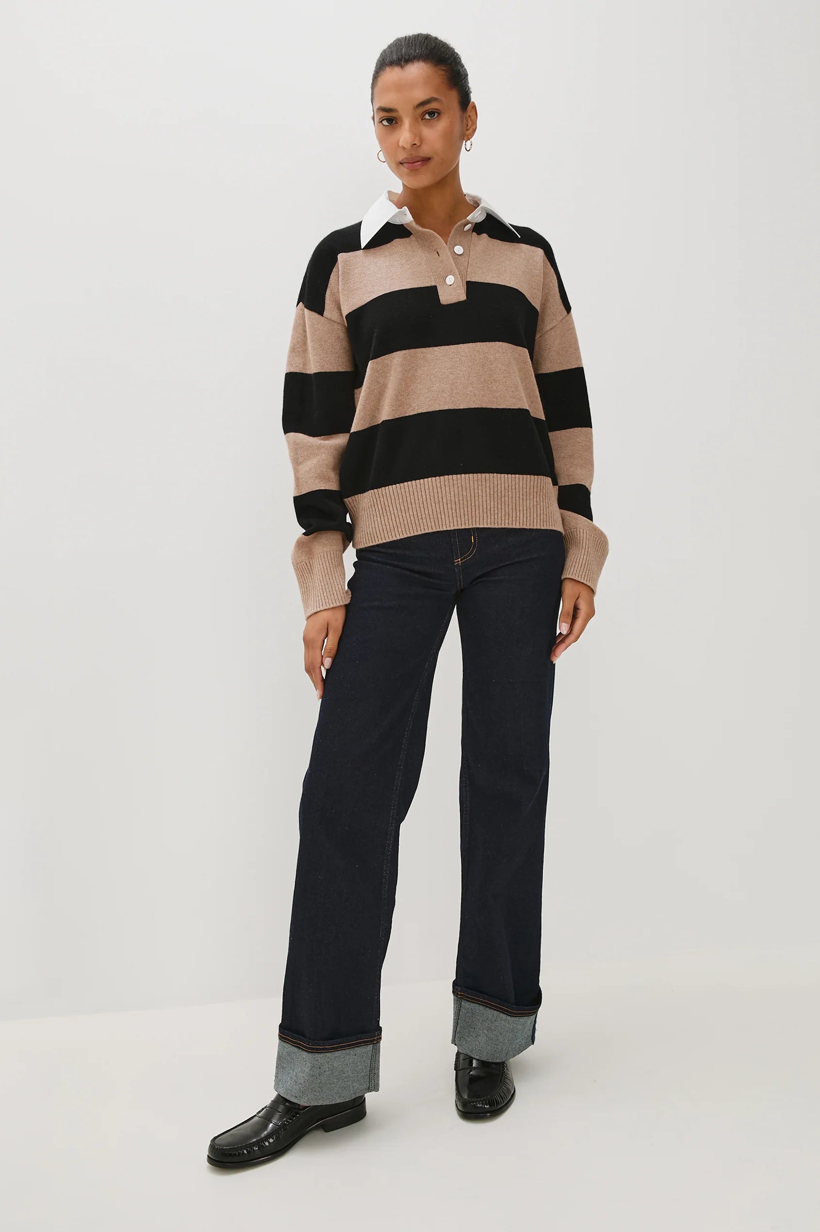 Person wearing a striped sweater and black pants on a white background