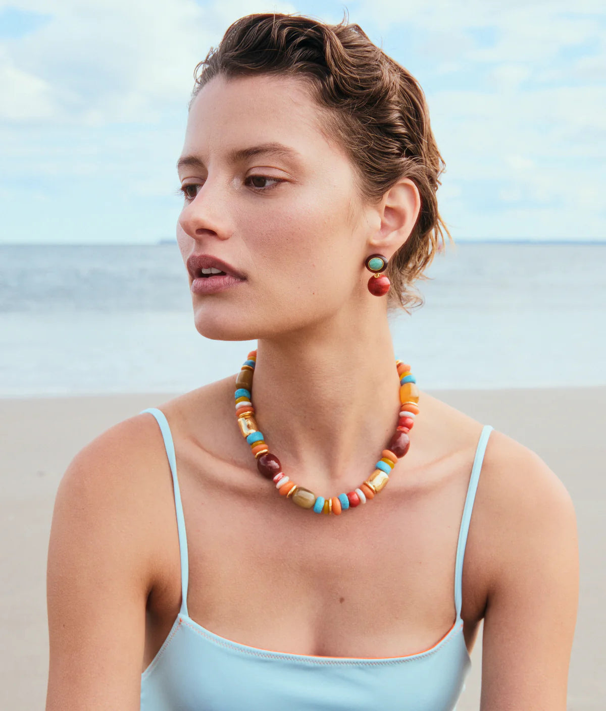Woman wearing Souvenir Necklace in Sienna and earrings on a beach