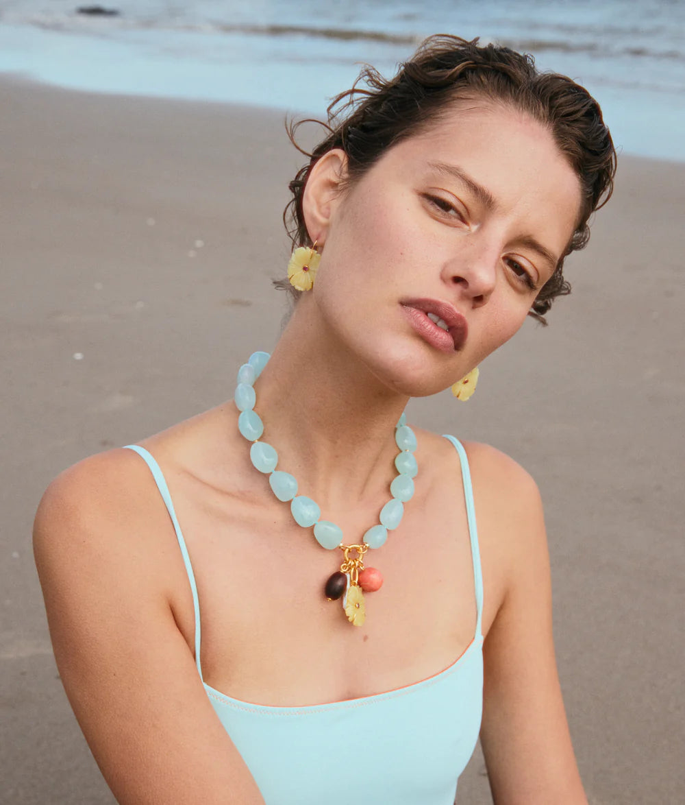 Woman on a beach wearing a light blue necklace with colorful pendants