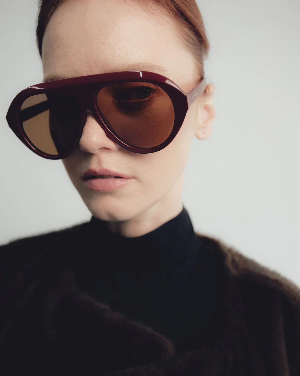model wearing garnet oversized sunglasses with a brown top on a white background 