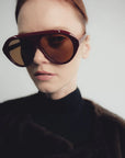 model wearing garnet oversized sunglasses with a brown top on a white background 