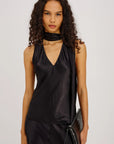 Woman wearing a black satin top and black pants against a plain background