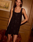 Nadia Dress front view at tilted angle with model in front of wooden wall