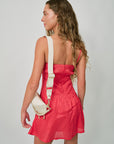Woman in a red dress with a white bag on a plain background, back view