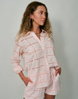 Woman wearing a light pink checkered outfit against a plain background with Cailynn Hoops