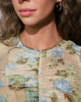 Close-up of a person wearing a floral-patterned garment with a necklace and earrings.
