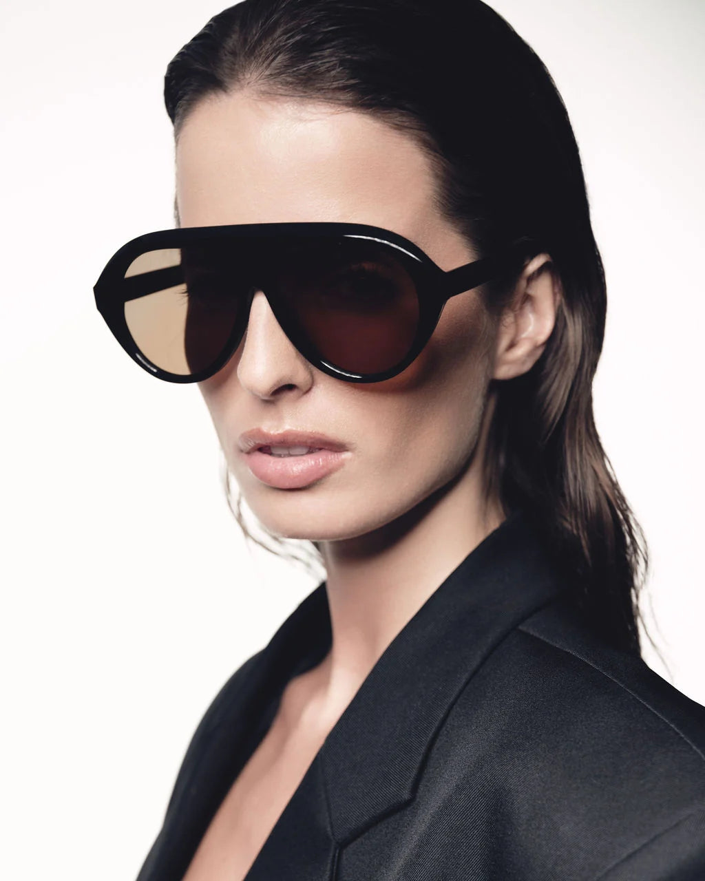Woman wearing a pair of large black sunglasses with a plain background