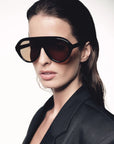 Woman wearing a pair of large black sunglasses with a plain background