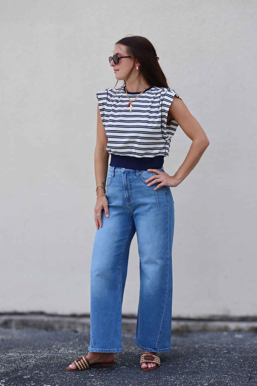 Woman wearing a striped top and blue jeans against a plain background