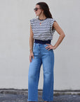 Woman wearing a striped top and blue jeans against a plain background