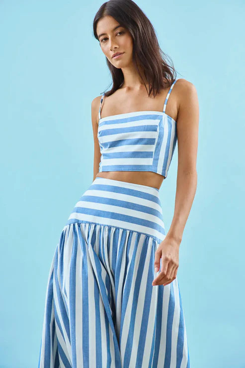 Woman wearing a blue and white striped outfit against a light blue background