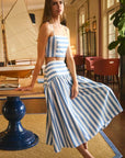 Woman in a blue and white striped outfit standing in a room with furniture and decor.