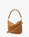 A camel brown suede shoulder bag with a curved top handle, a detachable shoulder strap, and gold-tone hardware, shown against a plain white background.