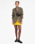 model wearing houndstooth blazer with yellow skirt and mahogany cross body bag