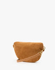 A small camel-colored suede crescent-shaped shoulder bag with a tan leather strap and gold-tone hardware, photographed on a clean white background.