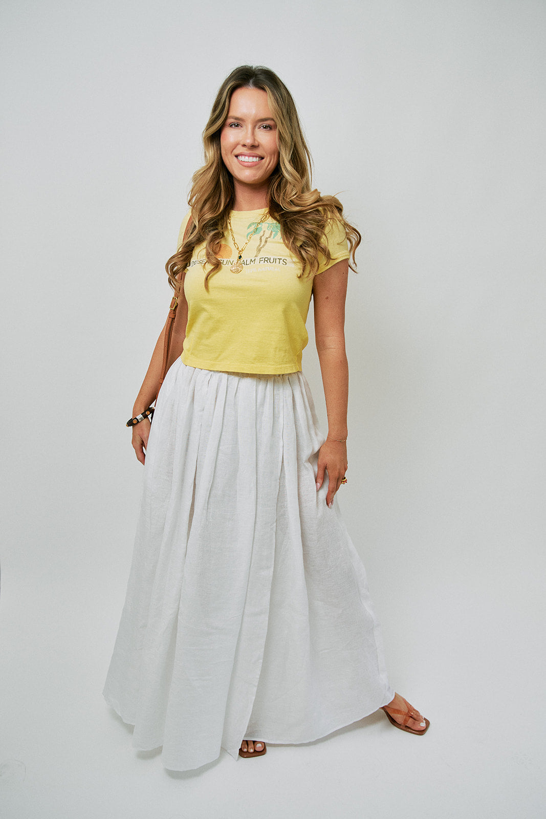 Woman wearing a yellow top and white skirt on a plain background