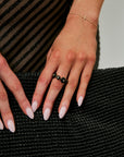 Close-up of a hand wearing a black ring on a textured black surface