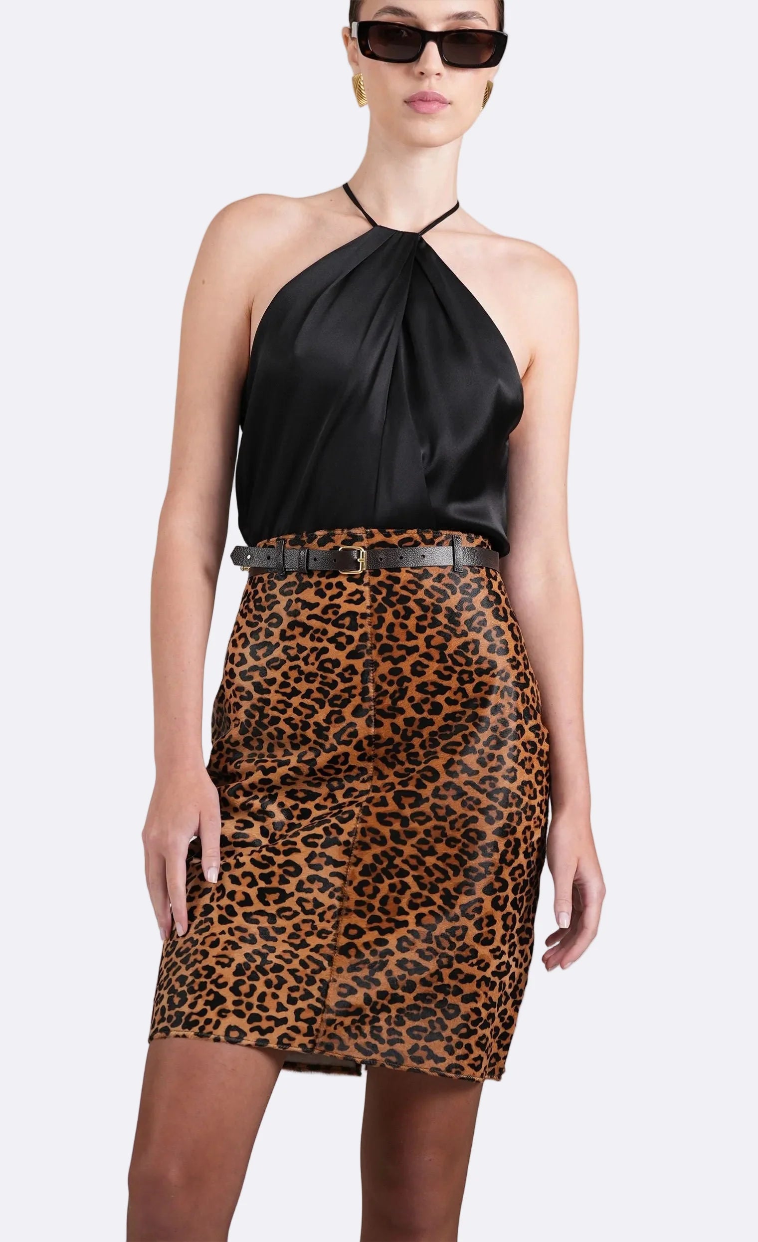 Woman wearing a black halter top and leopard print skirt on a white background