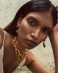 Woman wearing gold chain necklace and earrings with a neutral background