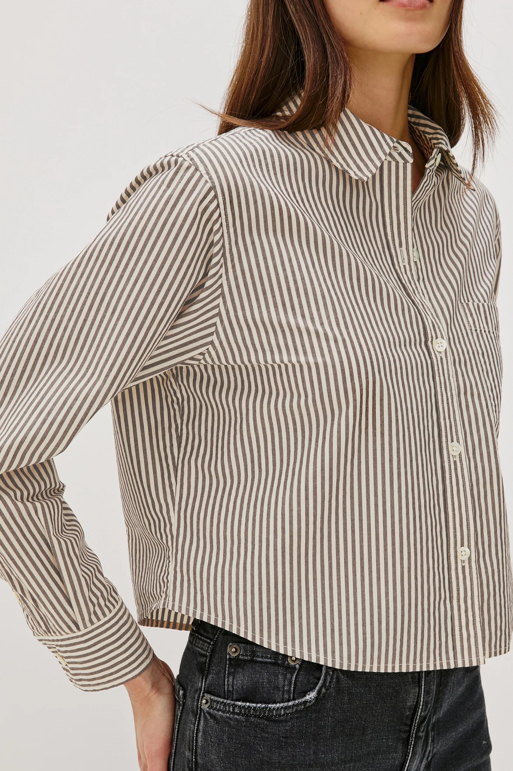 Woman wearing a striped shirt with a neutral background side view