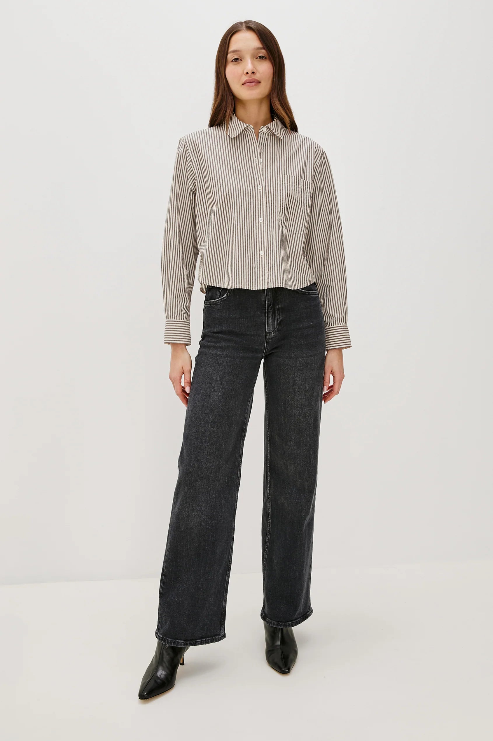 Woman wearing a striped shirt and black jeans on a white background front view