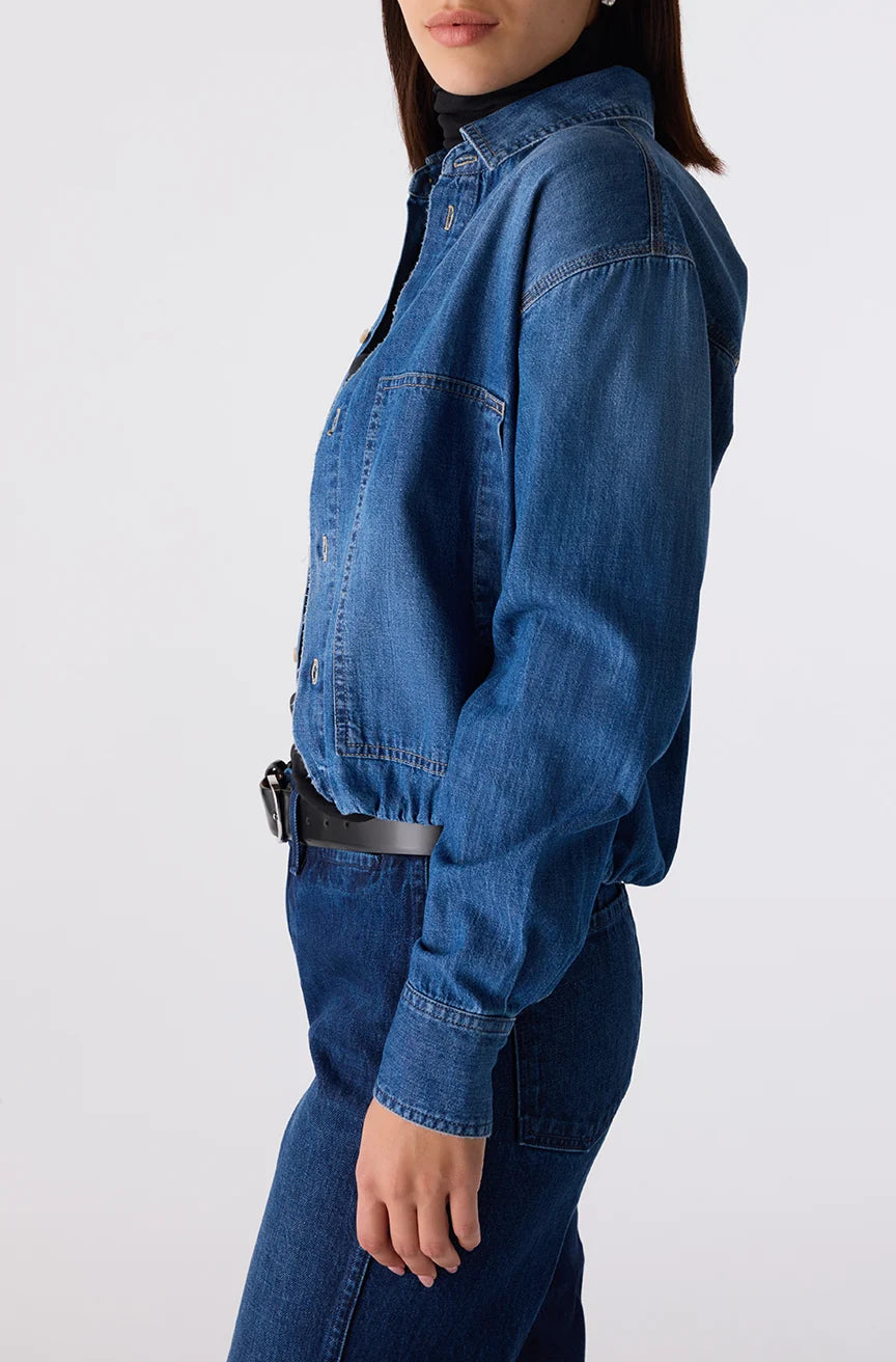 Person wearing a blue denim jumpsuit on a white background