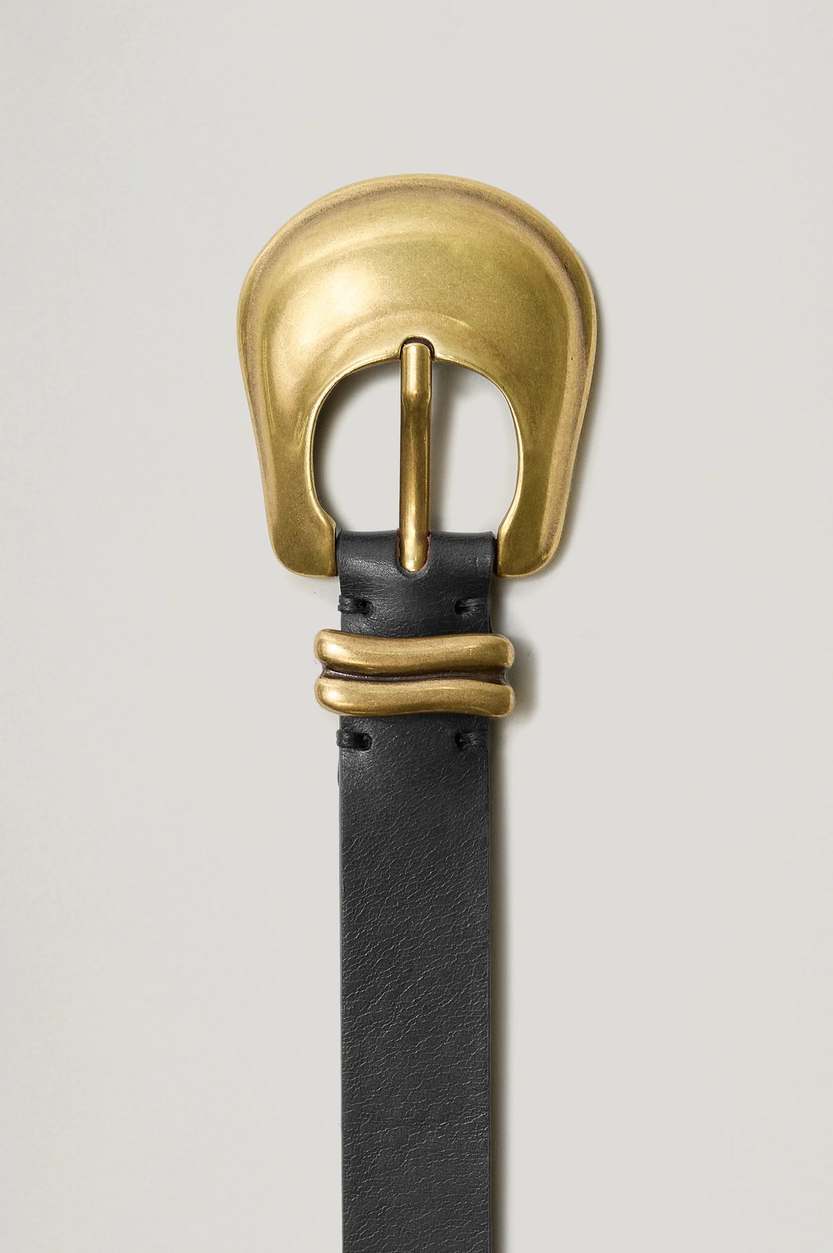 Black leather belt with a gold buckle on a light gray background