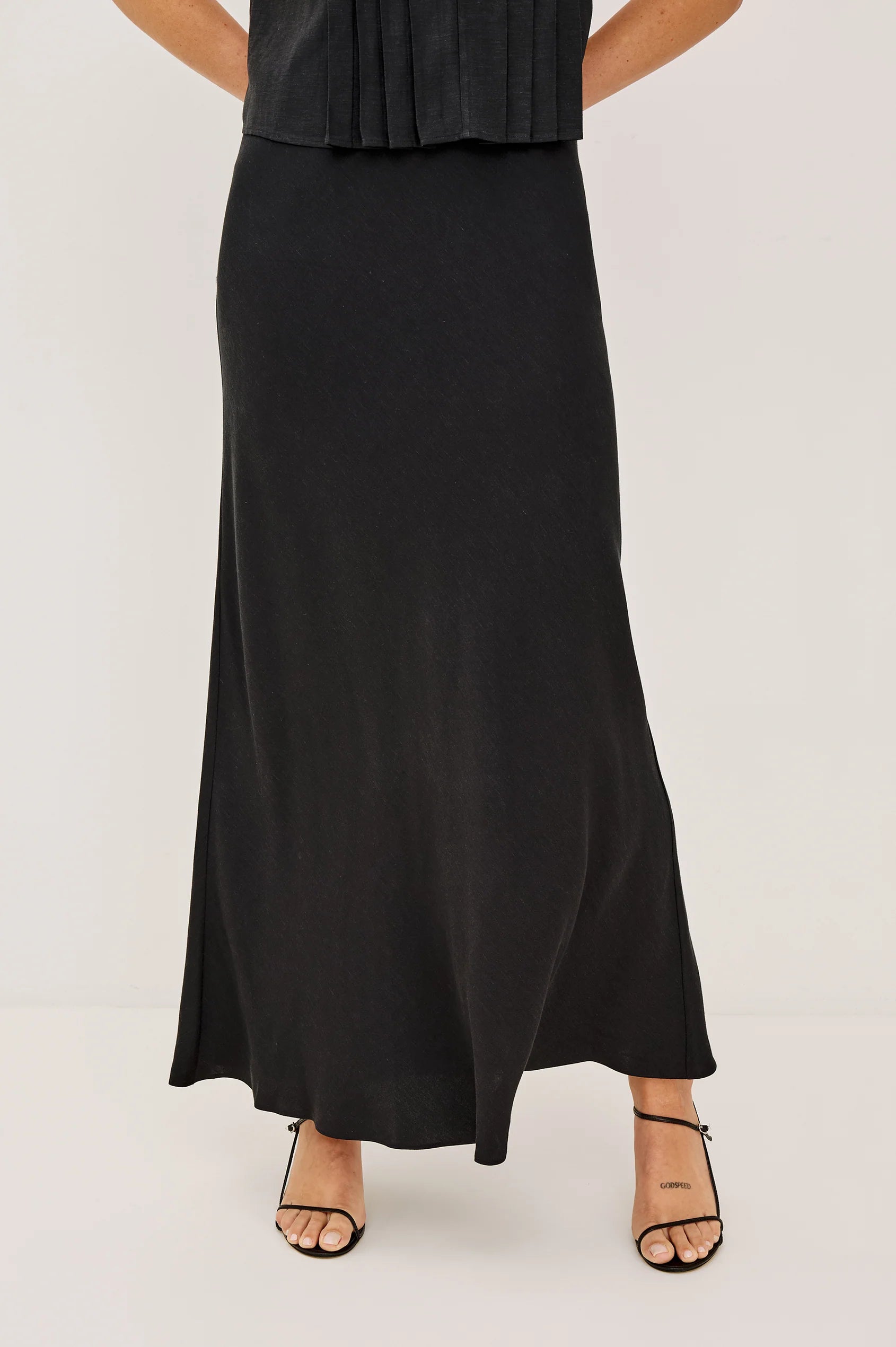 Person wearing a black dress with a plain background